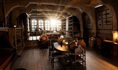 an old fashioned living room with wood flooring and stone arches on the ceiling is lit by sunlight streaming through windows