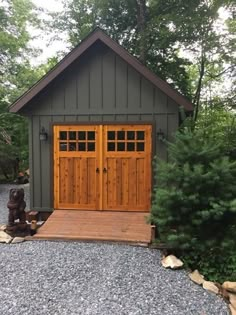 two wooden doors are on the side of a small shed with gravel and rocks around it