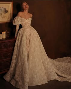 a woman in a white dress standing next to a dresser