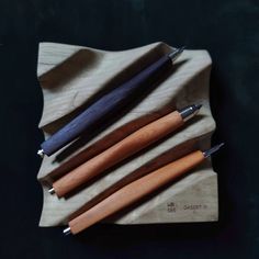 five different types of pens sitting on top of a wooden napkin next to each other