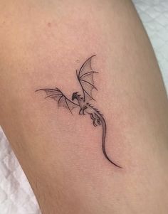 a small black dragon tattoo on the right side of the leg, it appears to be flying