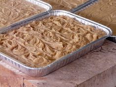 two pans filled with food sitting on top of a wooden table next to each other