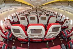 the inside of an airplane with rows of red and white seats on each side, facing forward