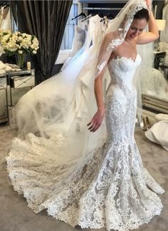 a woman wearing a wedding dress and veil standing in front of a mirror with her hand on her head