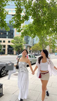 two women walking down the street holding hands