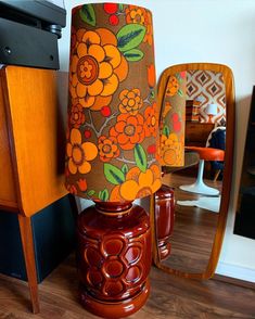 a lamp sitting on top of a wooden table next to a mirror and chair in a room