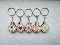 six cross stitch keychains with different designs on them