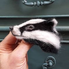 a hand holding a needle felt badger in front of a drawer