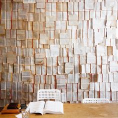 an open book sitting on top of a wooden table next to a wall covered in books