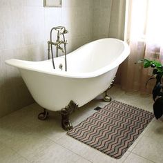 a bath tub sitting next to a toilet in a bathroom with a rug on the floor