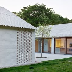 the house is made out of white bricks and has an open patio area with sliding glass doors