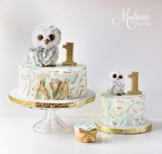 two cakes decorated with white frosting and gold decorations, one has an owl figurine on top