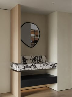 a marble bench in front of a mirror on the wall and wooden floor below it