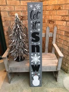 a wooden sign that says let it snow next to a chair with a christmas tree