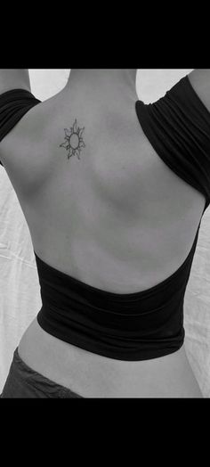 a woman with a sun tattoo on her upper back neck and shoulder, in black and white