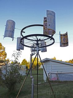 an old fashioned spinning wheel with beer cans hanging from it's sides in front of a house