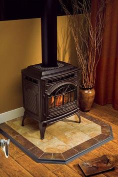 a wood burning stove sitting on top of a wooden floor next to a potted plant