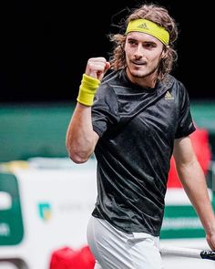 a male tennis player is holding his fist in the air and wearing a yellow headband