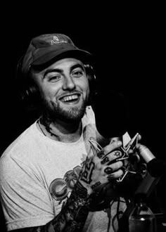 a black and white photo of a smiling man with headphones in front of a microphone