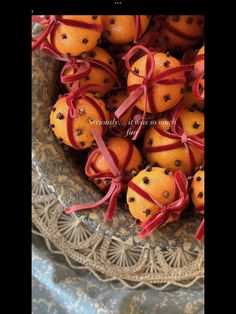 oranges wrapped in red ribbon sit in a bowl on a lace doily, ready to be eaten