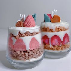 two desserts with strawberries, cream and other toppings in small glass containers