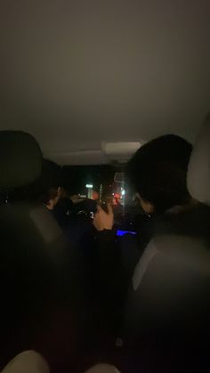 two people sitting in the back seat of a car at night with city lights behind them