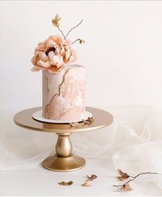 there is a pink cake with flowers on the top and gold stand next to it