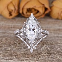 an engagement ring with a pear shaped diamond center surrounded by small round diamonds on a wooden surface