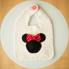 a crocheted bib with a red bow on it and a minnie mouse head