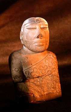 an ancient statue sitting on top of a rock