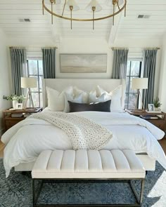 a large bed with white sheets and pillows in a room that has blue carpeting