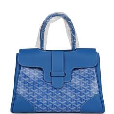 This Goyard Saigon soft tote is in blue Goyardine coated canvas and chevroches calfskin with palladium hardware, contrast stitching, features two double rolled top handles, signature Saigon leather strap and loop closure, and a cutout in the top of the flap for the handle to fit through.The Interior is lined is white canvas and blue chevroches calfskin, single floating pocket and a wooden detail on back of bag with palladium studs.Origin: FranceCondition: New and never worn (plastic on handles)Accompanied by: Goyard box, dustbag, felt, carebook, ribbonMeasurements: 13" x 9.5"x 6" Designer Blue Bag With Double Handle, Designer Blue Tote Bag, Designer Blue Tote Satchel, Blue Business Satchel Bag, Blue Satchel Bag For Business, Designer Blue Satchel Tote, Designer Blue Satchel Shoulder Bag, High-end Blue Tote Shoulder Bag, Blue Business Satchel With Top Carry Handle