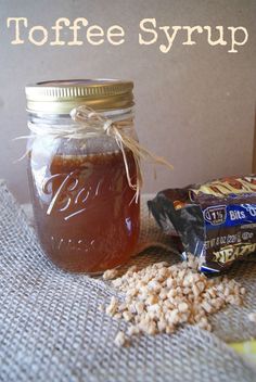 a jar filled with coffee syrup next to a bag of peanut butter and some peanuts