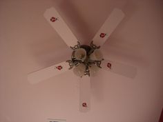 a white ceiling fan mounted to the side of a pink painted wall in a bedroom