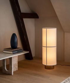 a lamp that is on top of a table next to a book and some books