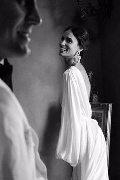 a black and white photo of a woman in a dress looking at another woman's face