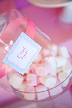 a glass bowl filled with marshmallows sitting on top of a pink table