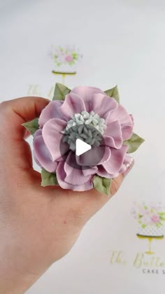 a hand holding a pink flower with green leaves