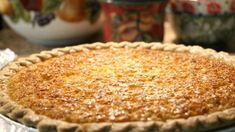 a pie sitting on top of a table next to bowls and plates filled with fruit