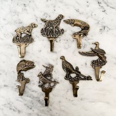 six antique style bird bottle openers on a marble surface