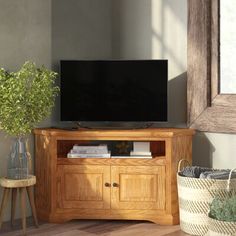 a wooden entertainment center with a flat screen tv on it's stand next to a potted plant