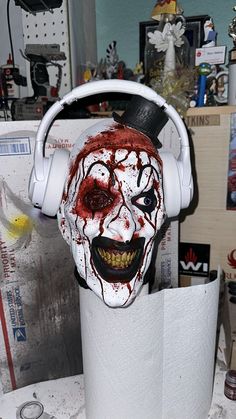 a white mask with headphones on top of a roll of toilet paper in a room