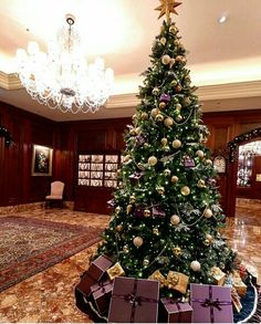 a christmas tree with presents under it in a hotel lobby decorated for the holiday season