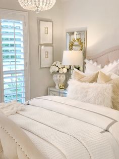 a bedroom with white bedding and chandelier in the corner next to a window