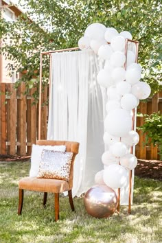 a chair and some balloons in the grass