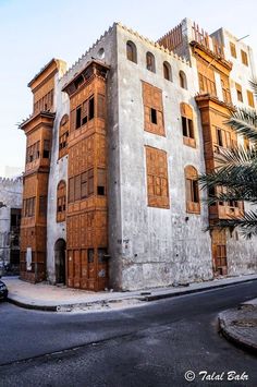 an old building with wooden shutters and palm trees on the street in front of it