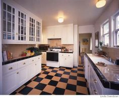 a kitchen with black and white checkered flooring next to a stove top oven