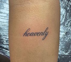 a woman's leg with the word heavenly tattooed on it, in cursive font