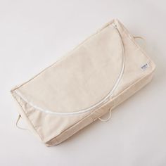 an empty canvas bag sitting on top of a white surface with no handles or straps