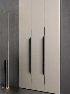 a tall white cabinet next to a black and gold lamp in a room with grey walls